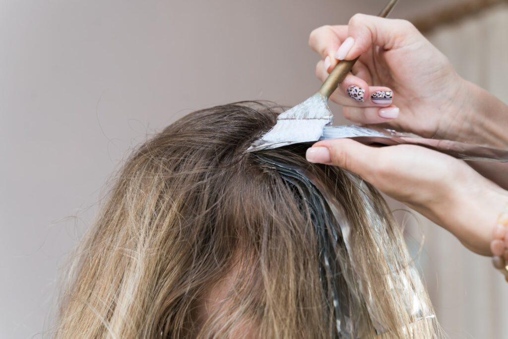 hairdresser makes hair coloring to young girl